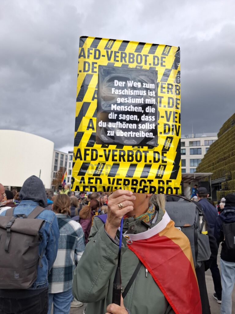 Plakat von der Prüf-Demo in Düsseldorf
Aufschschrift: Der Weg zum Faschismus ist gesäumt mit Menschen, die dir sagen, dass du aufhören sollst, zu übertreiben